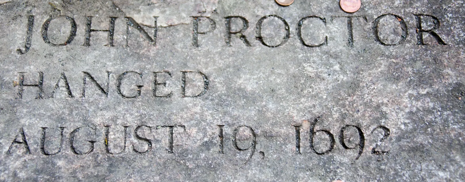 Stone marker engraved 'John Proctor Hanged August 19, 1692' at the Salem Witch Trials Memorial.
